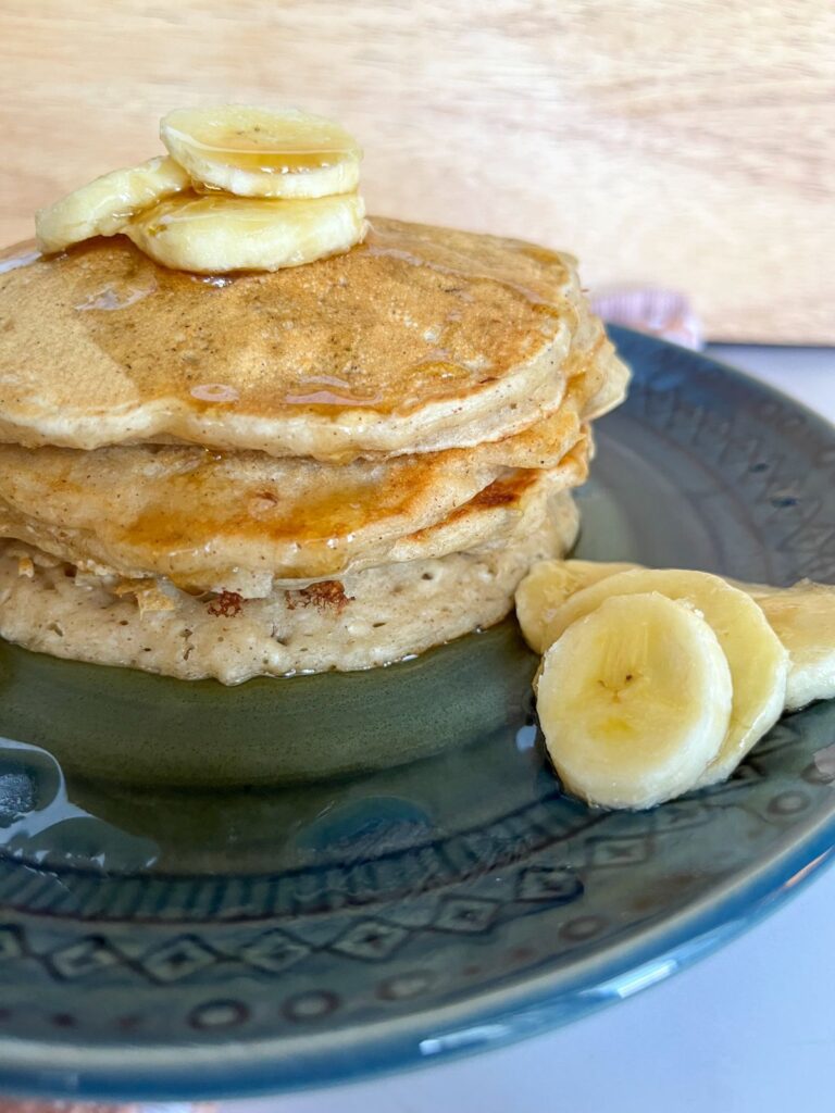 Banana pancakes without eggs stacked on top of each other and topped with sliced bananas