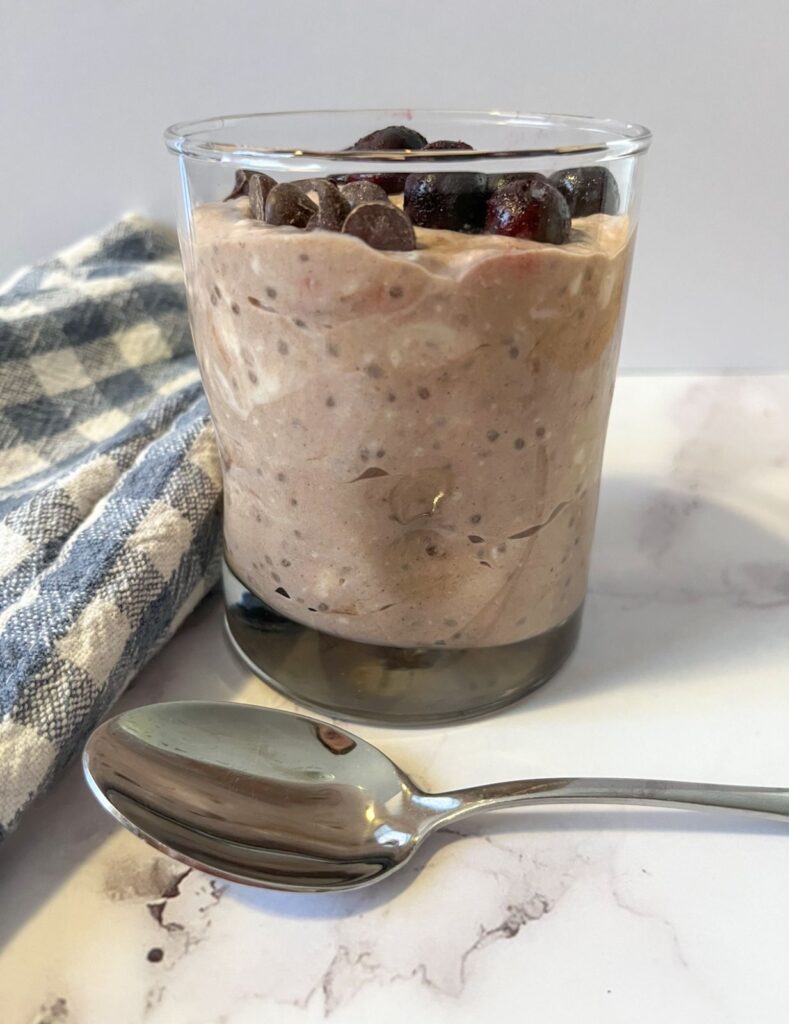 chocolate chia seed pudding served in a glass with blueberries and chocolate chip toppings