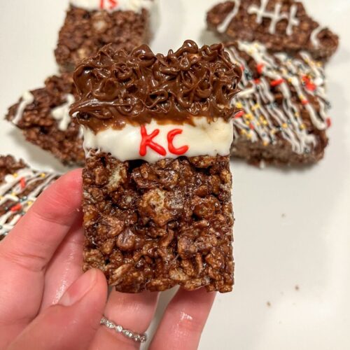 a hand holding a rice krispie treat decorated for kansas city football