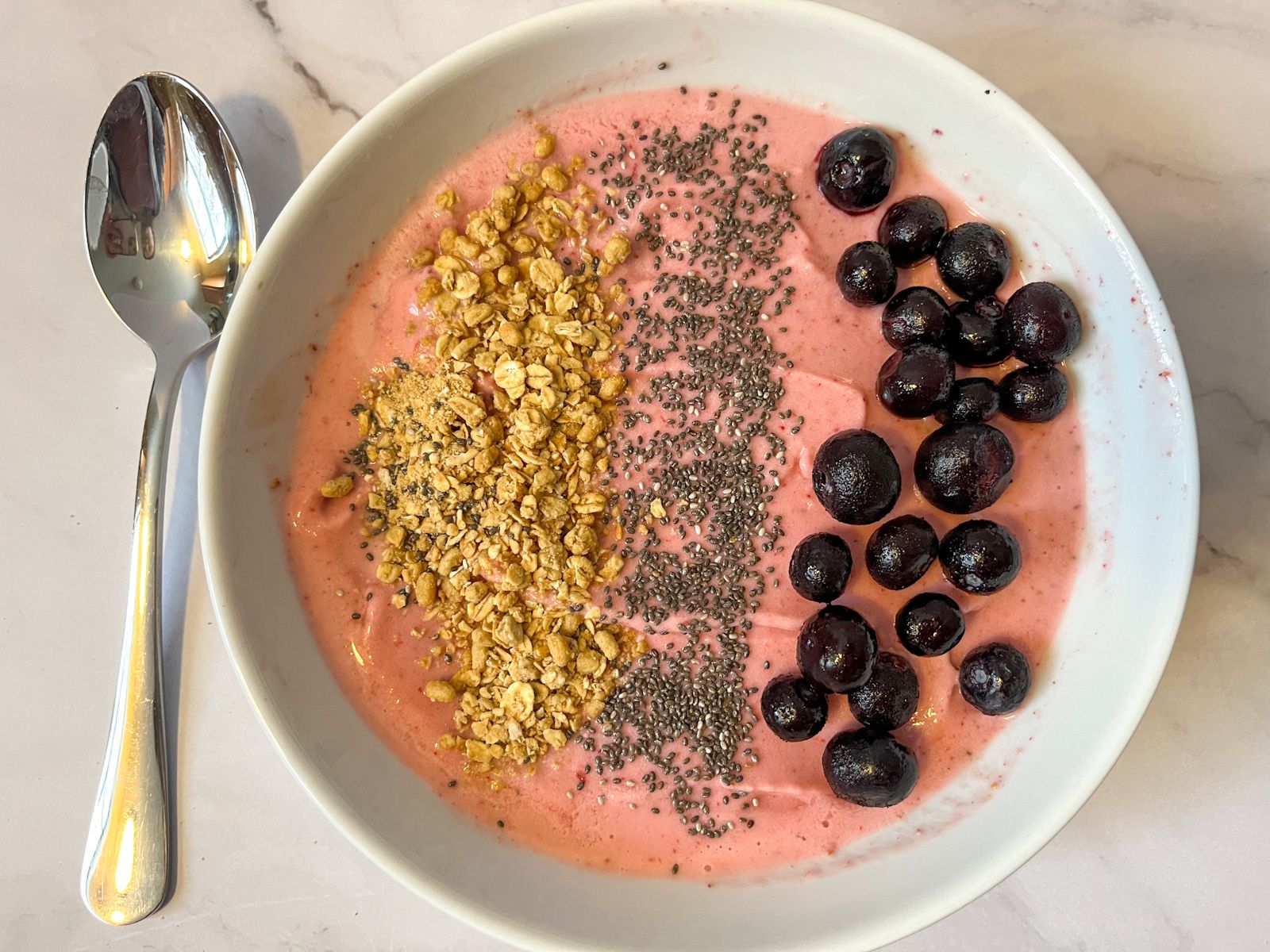 strawberry smoothie bowl with a spoon served next to it