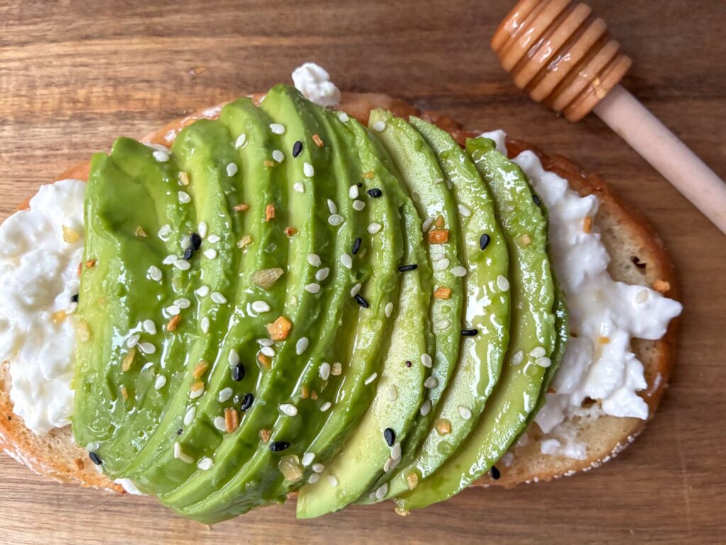 Piece of cottage cheese avocado toast with a honey wand about it
