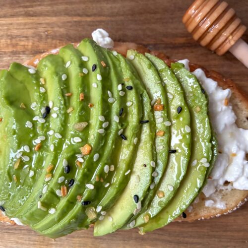 Piece of cottage cheese avocado toast with a honey wand about it