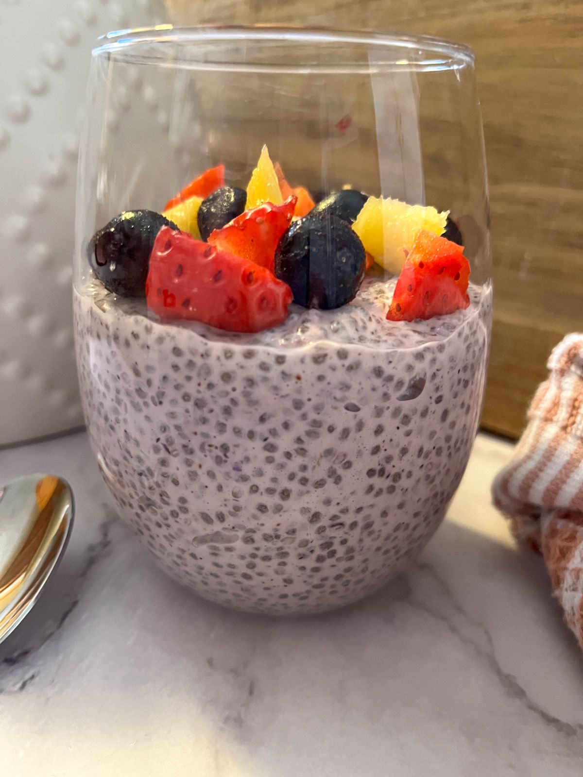 Berry chia seed pudding in a glass with chopped fruit on top