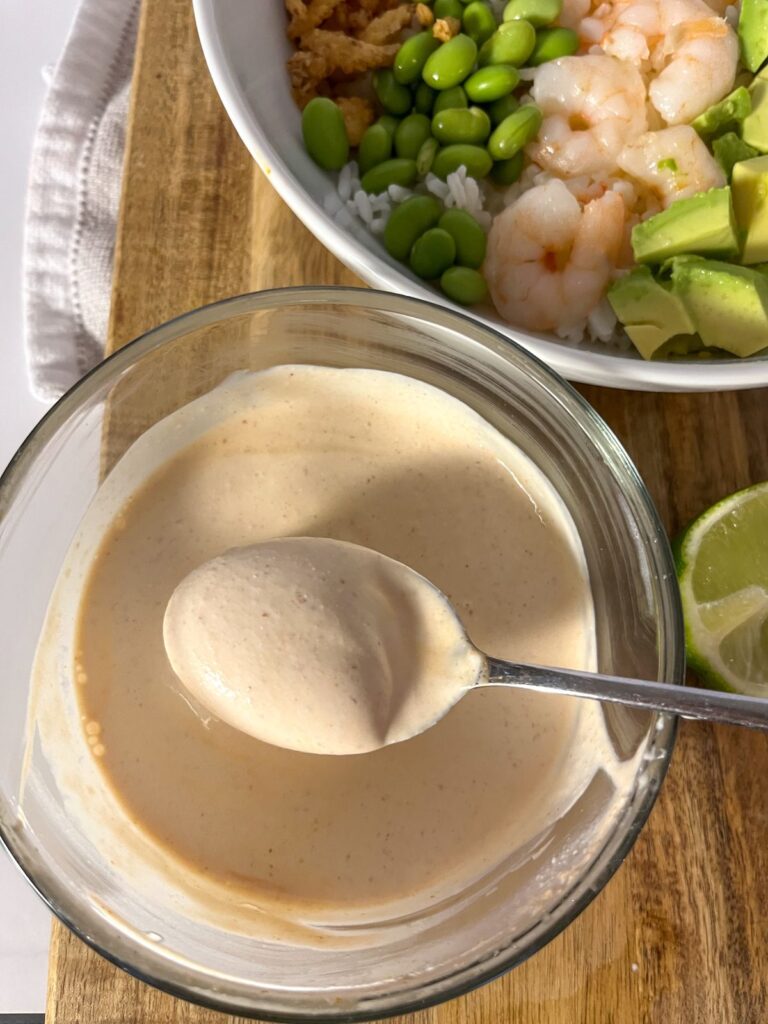 a bowl of creamy siracha sauce in a bowl with a spoon dipping it out