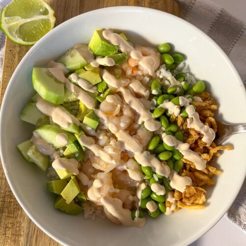 shrimp and rice bowl served in bowl with cream sauce drizzled on
