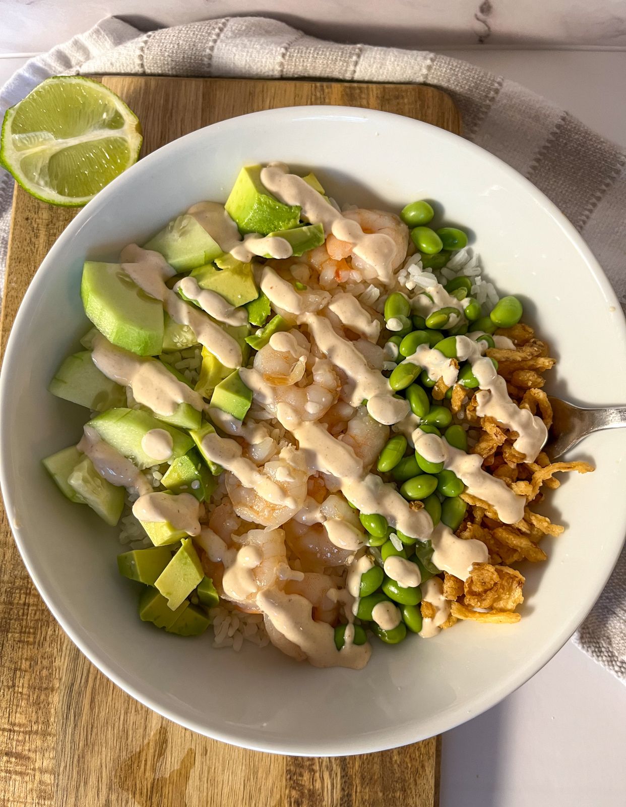 shrimp and rice bowl served in bowl with cream sauce drizzled on