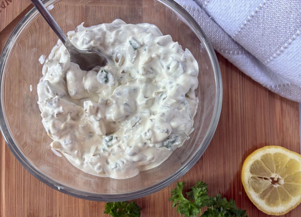Tartar sauce without mayonnaise served in a bowl with a lemon slice next to it