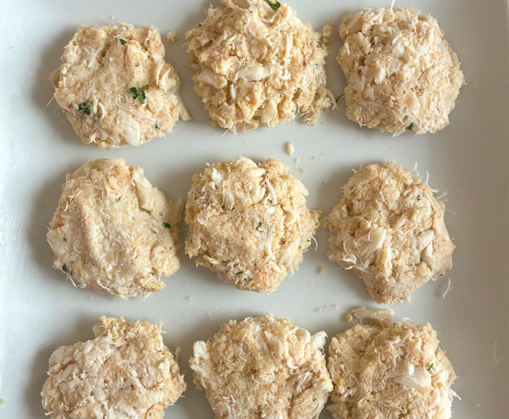 12 crab cakes before being cooked on a plate