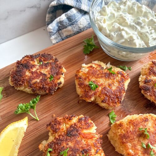 Eggless Crab Cakes laid out on a cutting board with a bowl of tartar sauce