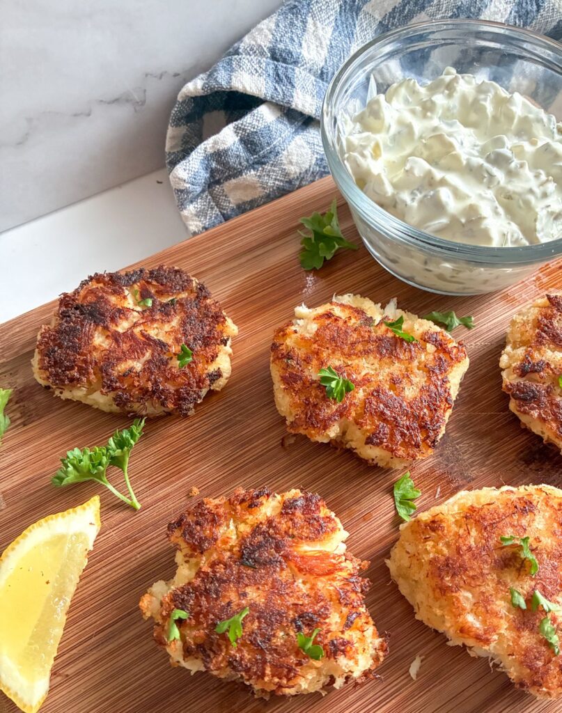 Eggless Crab Cakes laid out on a cutting board with a bowl of tartar sauce