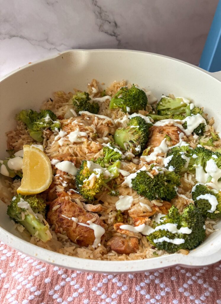 chicken and rice skillet still in the skillet with cream sauce drizzled on top.