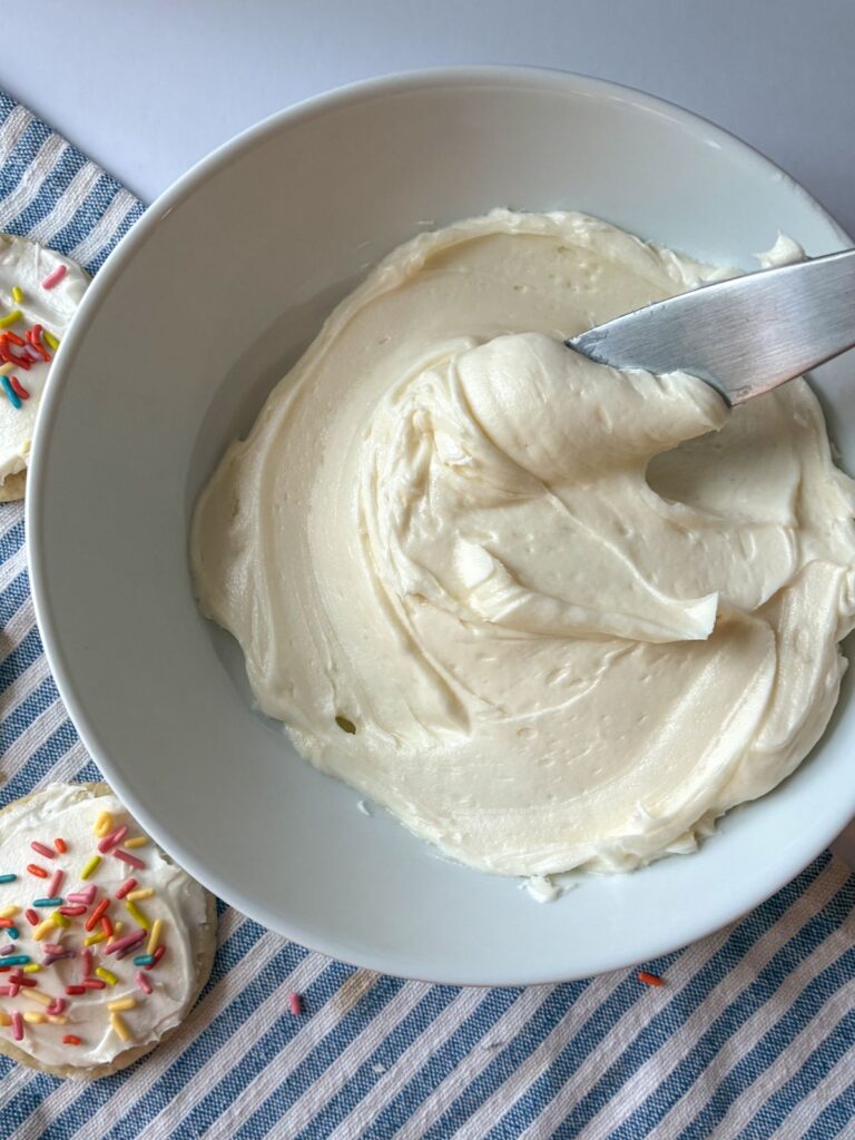vanilla frosting in a bowl with a knife scooping it out