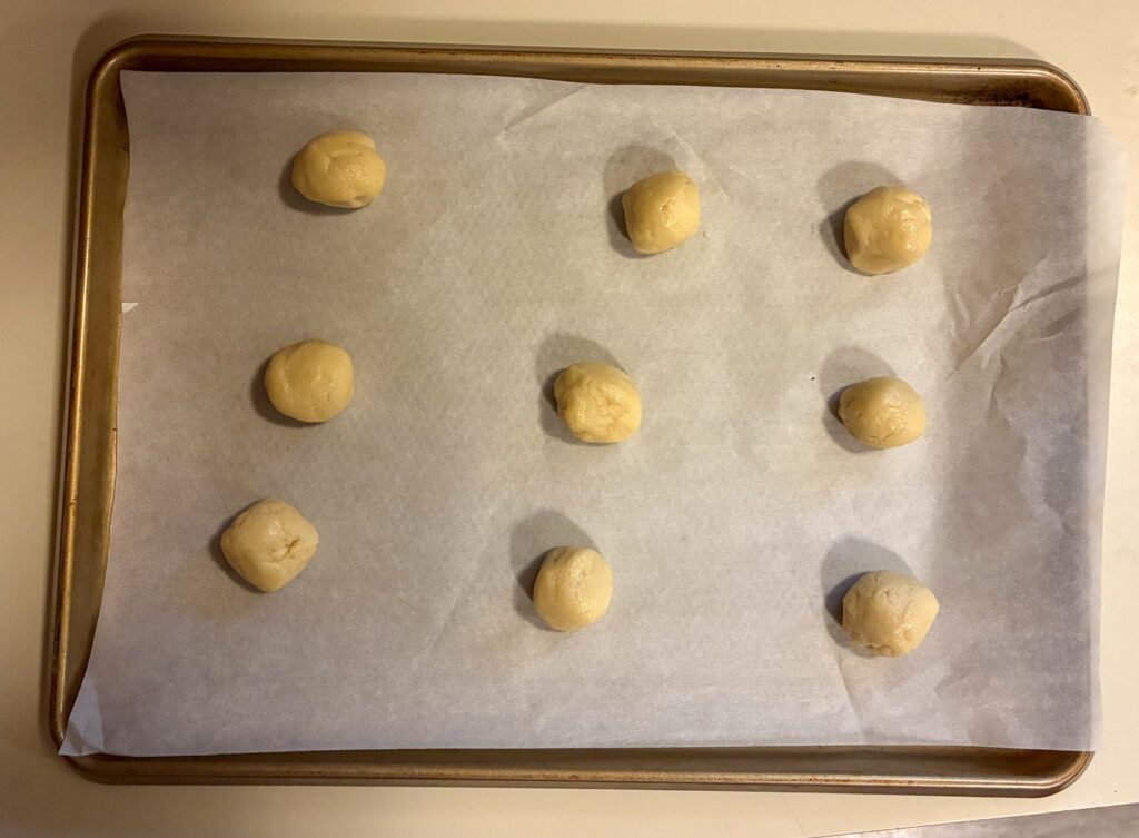 Nine dough balls on a baking sheet