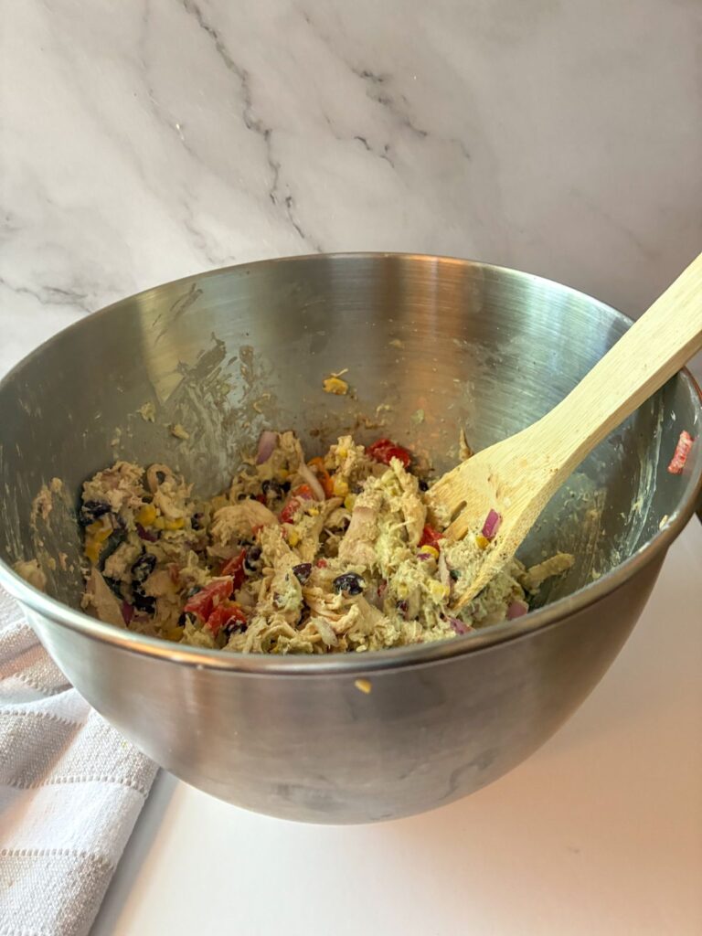 Southwest chicken salad in a large bowl with all ingredients tossed together with the dressing on it.