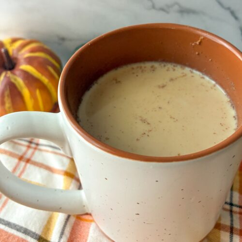 Pumpkin chai tea latte served in a mug with a little pumpkin sitting next to it