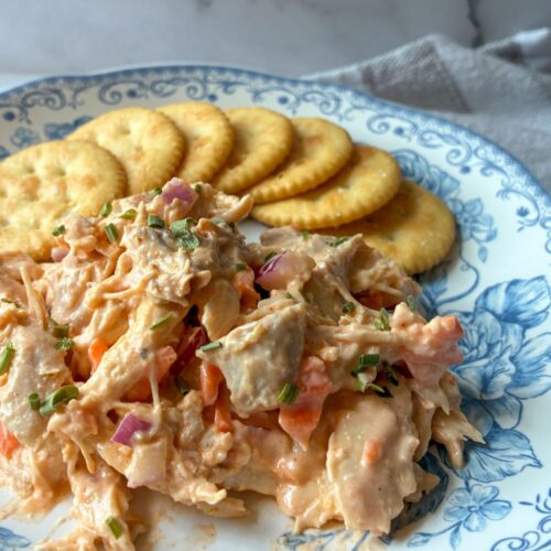 buffalo chicken salad served on a plate with crackers behind it