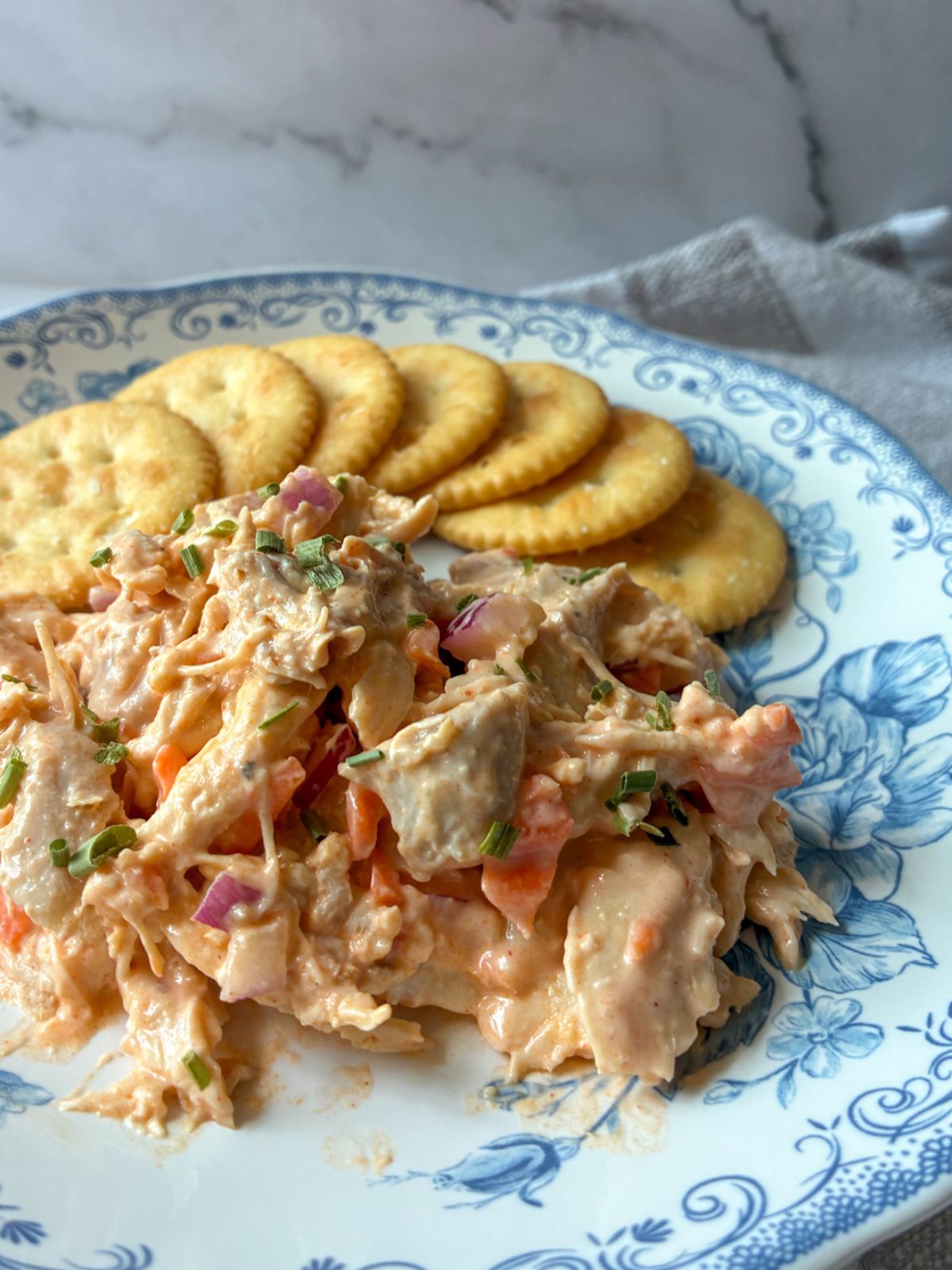 buffalo chicken salad served on a plate with crackers behind it