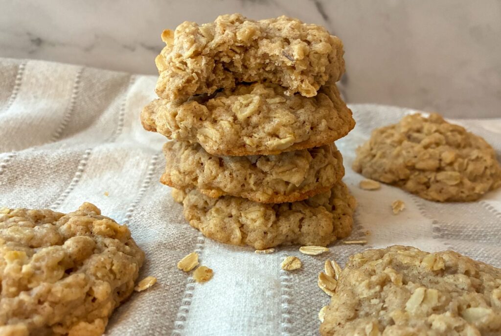 A stack of eggless oatmeal cookies and the one has a bite out of it.