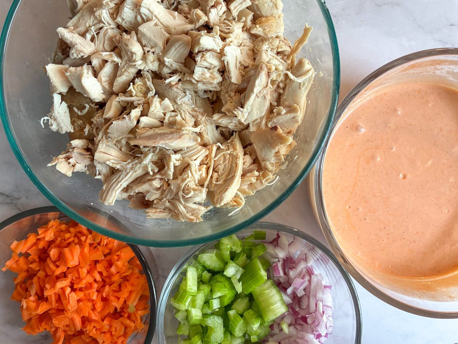 four bowls filled with the individual ingredients and one of them has the buffalo sauce.