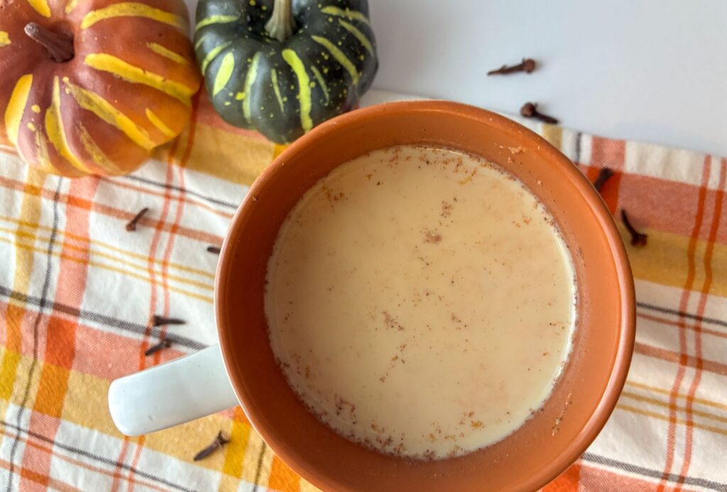 pumpkin chai tea latte with two pumpkins by its side.