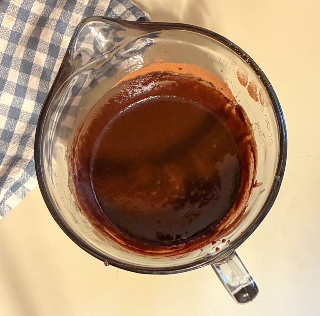 Large mixing bowl with melted butter, sugar, and cocoa powder mixed together