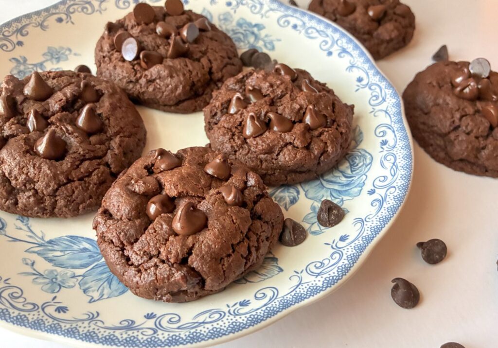 Eggless Double chocolate cookies on a plate and some on the table next to them.