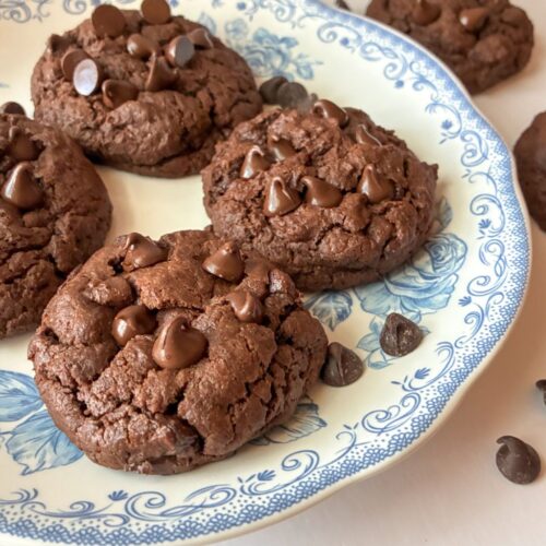 Eggless Double chocolate cookies on a plate and some on the table next to them.