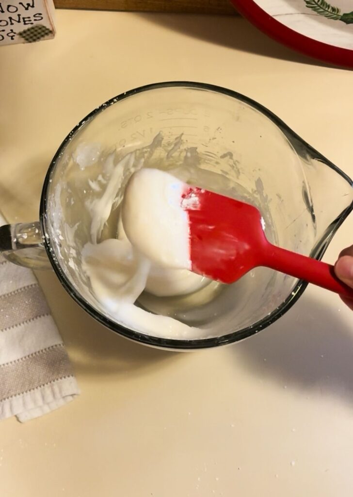 Royal icing mixed in a large bowl with a spatula scooping it out