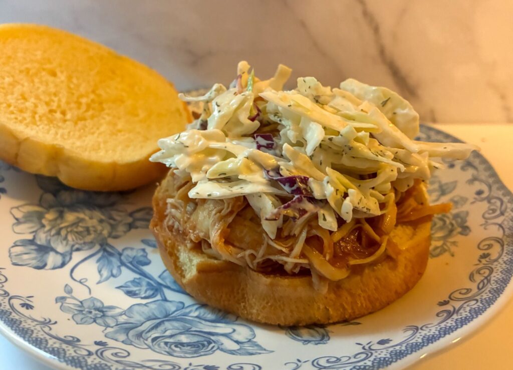 Slow cooker BBQ pulled pork on a bun with coleslaw on top