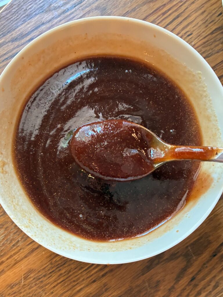 BBQ sauce mixed in a bowl with a spoon scooping it out