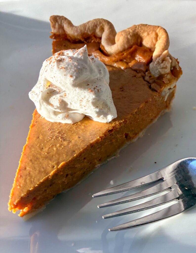 eggless pumpkin pie on a plate with whipped cream and a fork next to it