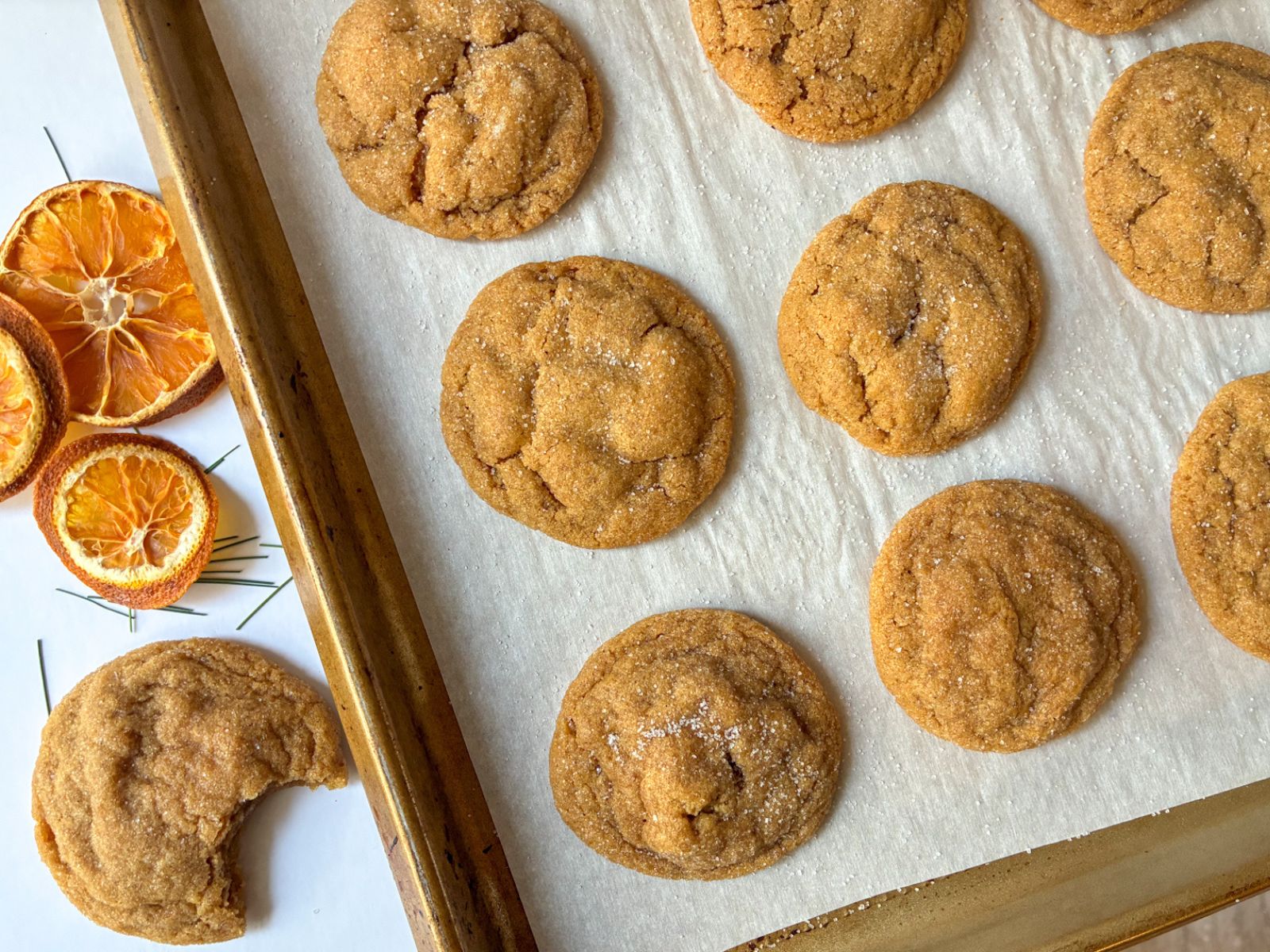 Baking sheet with eggless molasses cookies and a cookie next to baking sheet