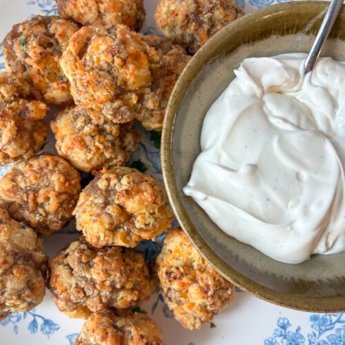 Sausage balls served on a plate with a bowl of dipping sauce next to it
