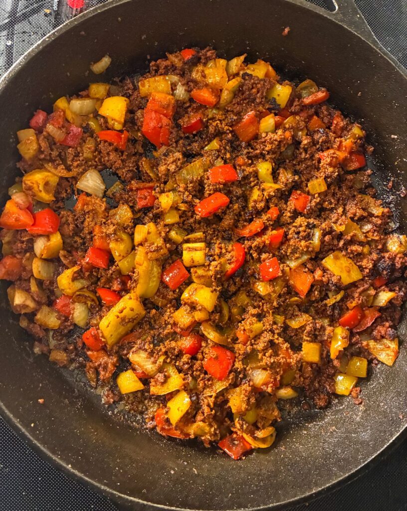 Chorizo and vegetables in a large cast iron skillet after its been cooked