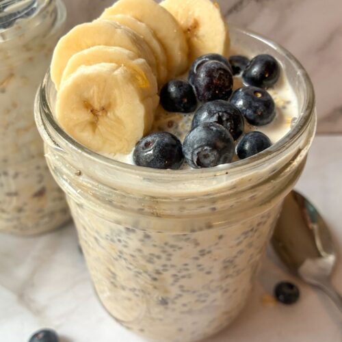 Two jars of overnight oats topped with blueberries and bananas