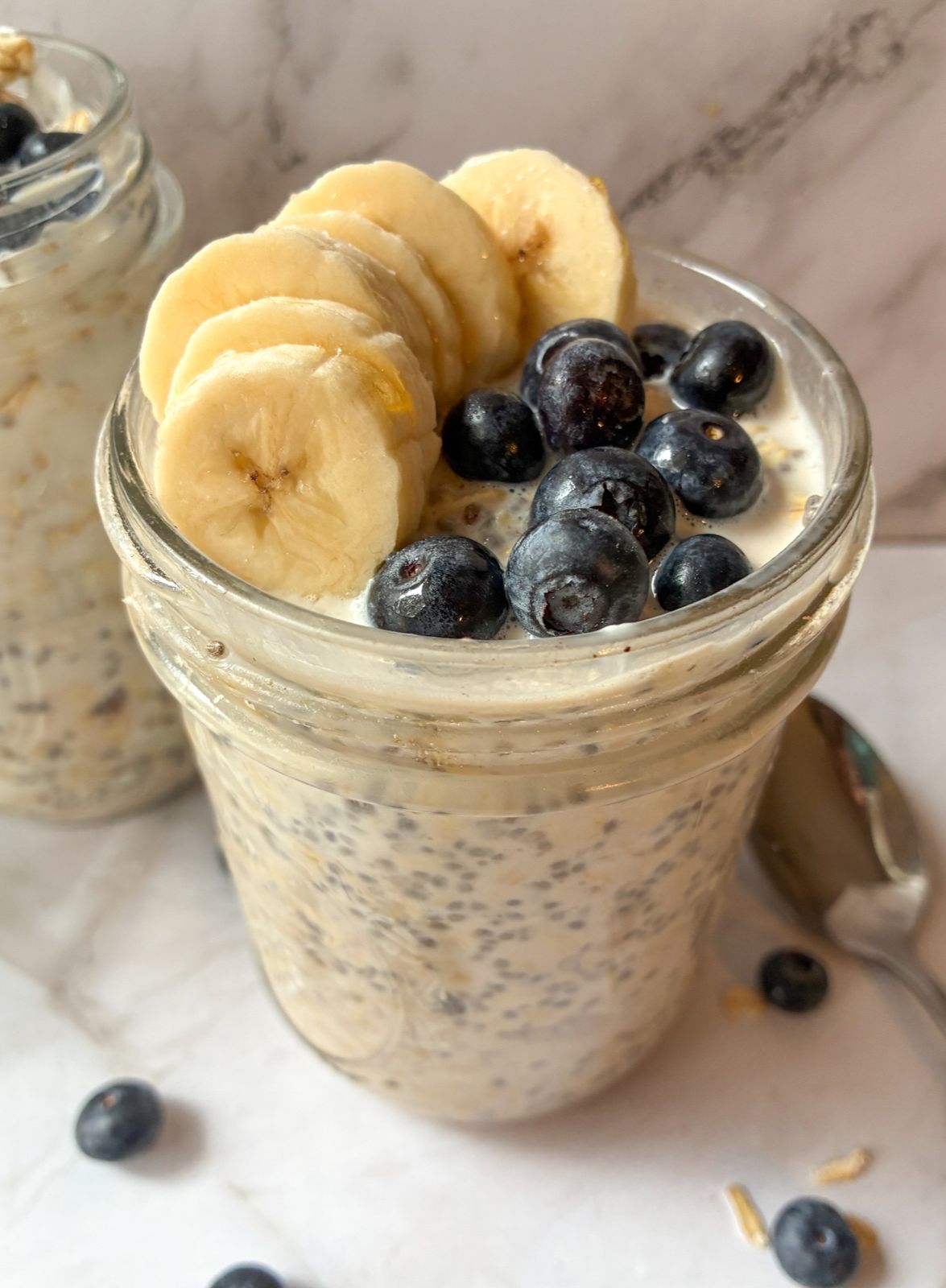 Two jars of overnight oats topped with blueberries and bananas