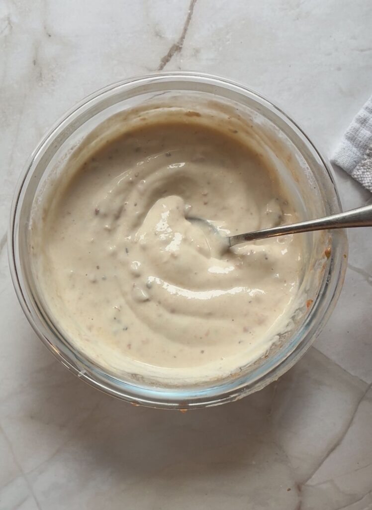 Greek cream sauce in a small bowl with a spoon in it