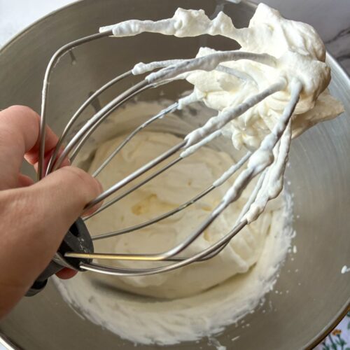 2 ingredient whipped cream on a whisk held over the metal bowl