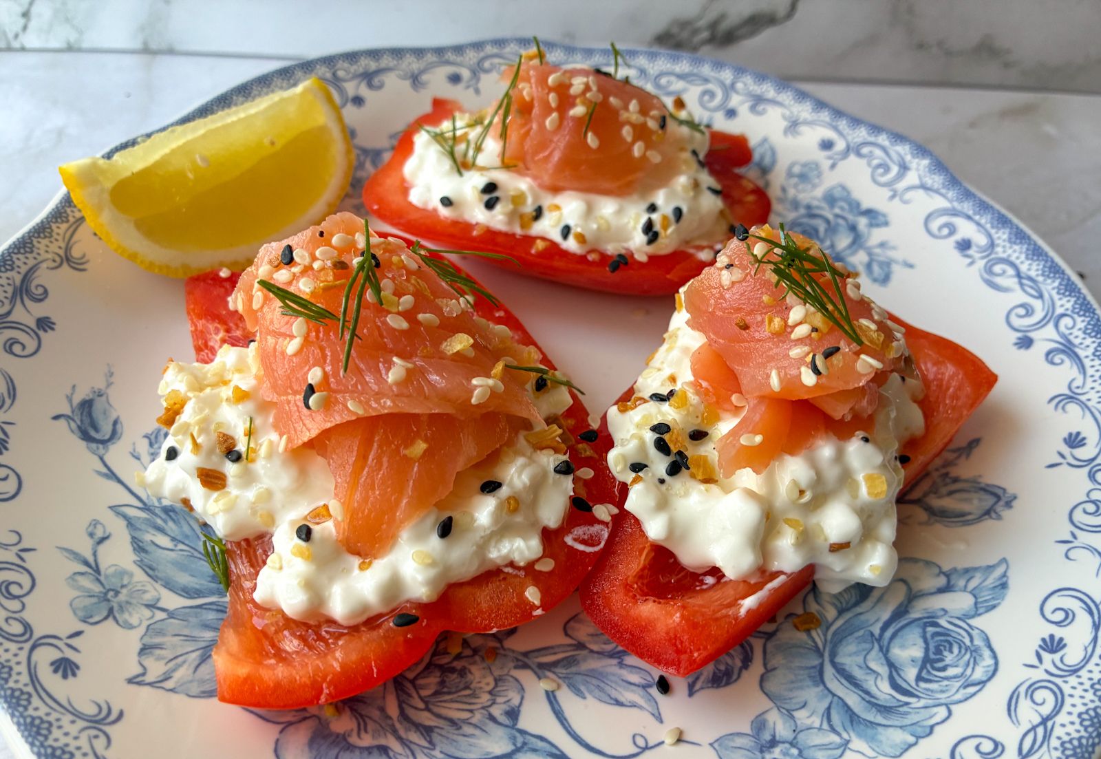 3 Cottage Cheese Stuffed Bell Peppers with Smoked Salmon on a plate with a lemon wedge