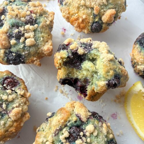6 eggless lemon blueberry muffins one with a bite taken out of it