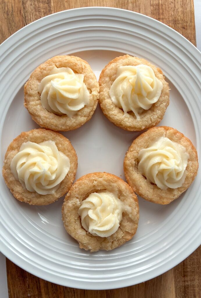 five eggless mini tarts on a plate with cream cheese filling piped into them