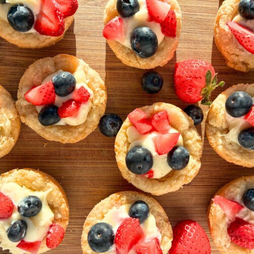 10 eggless sugar cookie mini tarts with fruit sprinkled all around them