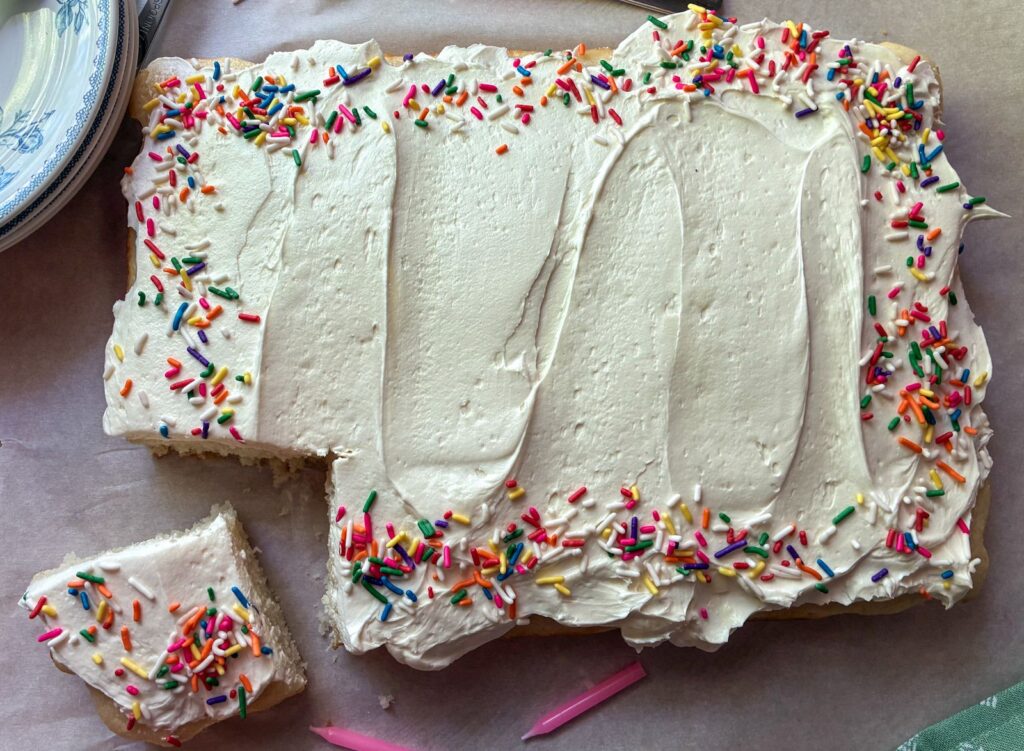 Top view of eggless vanilla sheet cake with a slice taken out of it