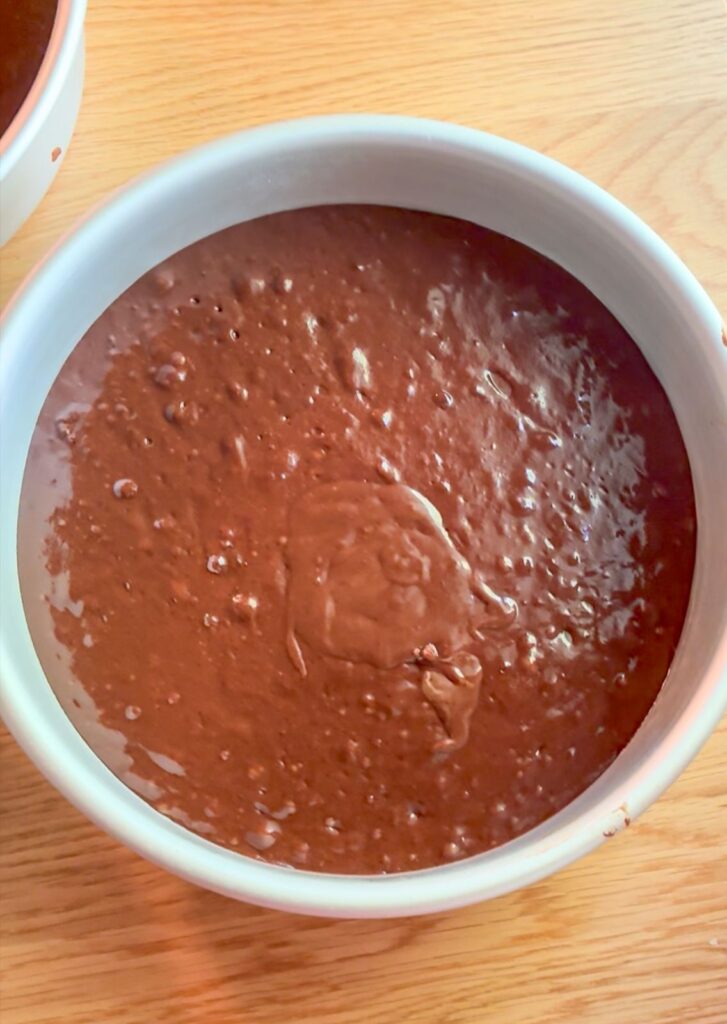 Cake batter poured into cake pans for eggless chocolate cake