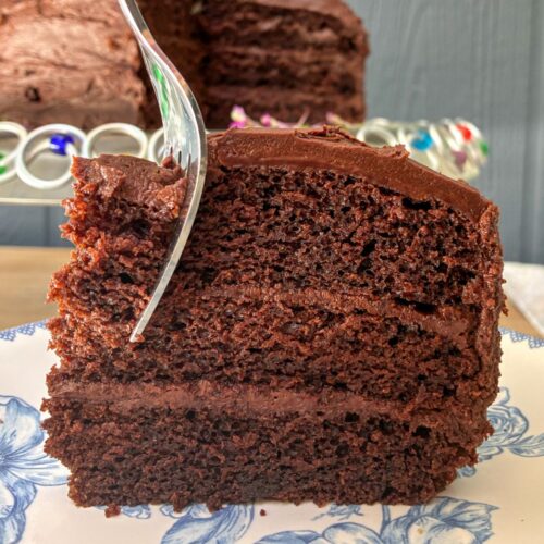 A slice of eggless chocolate cake with a fork going through it
