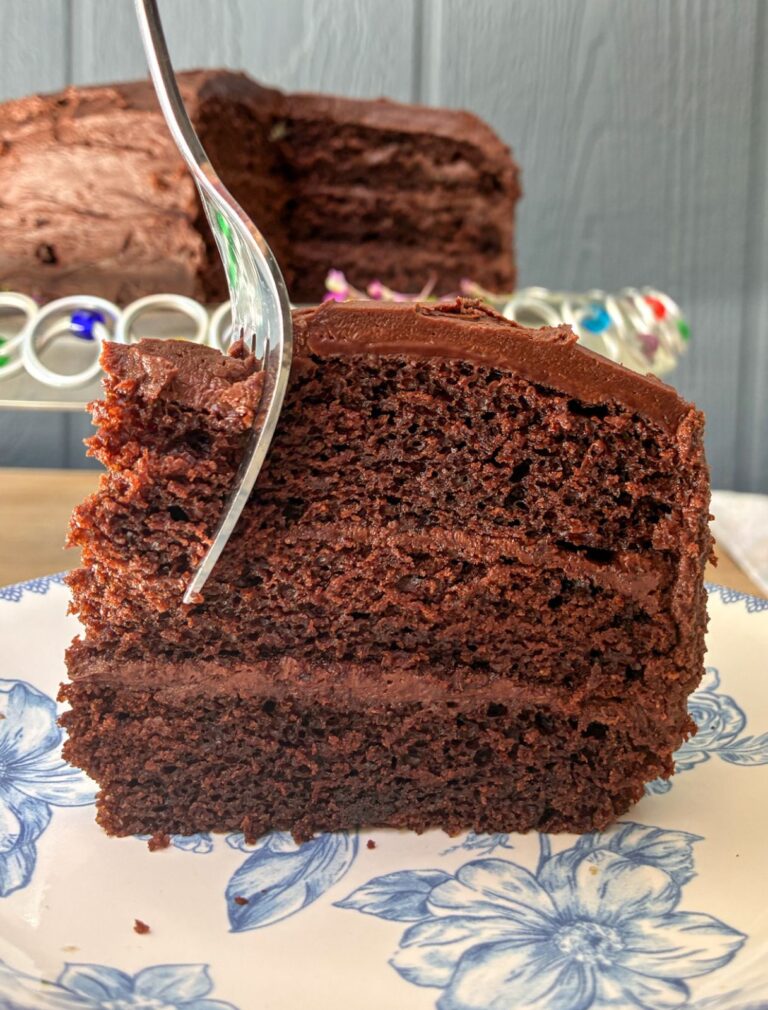 A slice of eggless chocolate cake with a fork going through it