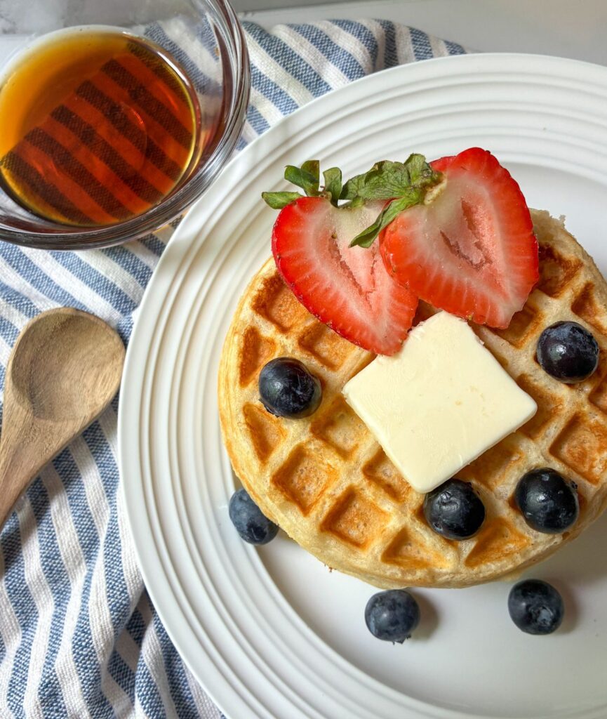 eggless waffles on a plate with fruit and butter on top