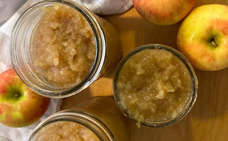 applesauce filled in mason jars surrounded by apples