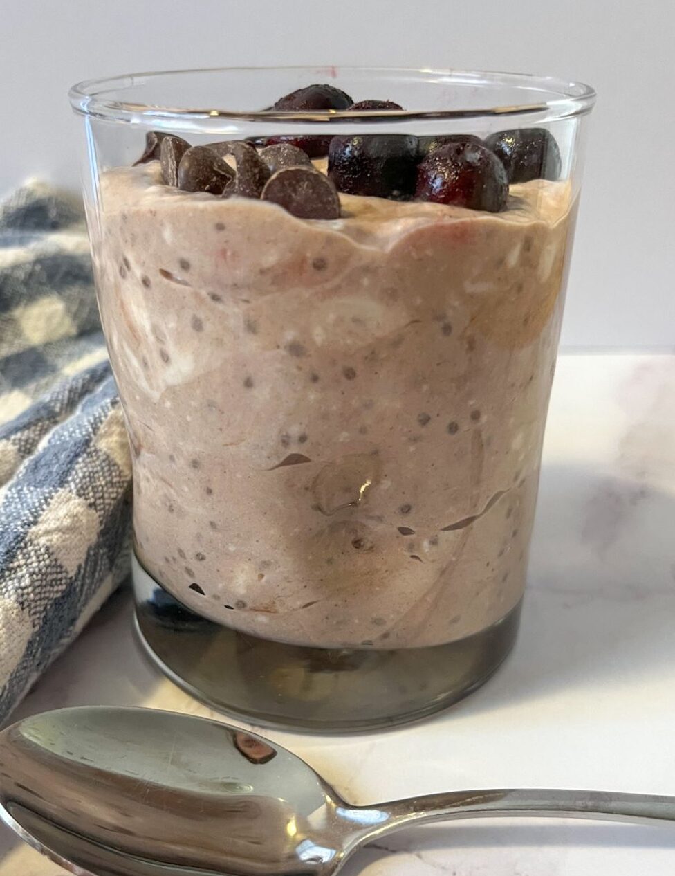 chocolate chia seed pudding served in a glass with blueberries and chocolate chip toppings