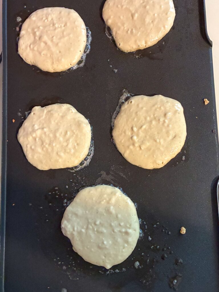 5 eggless protein pancakes on a griddle